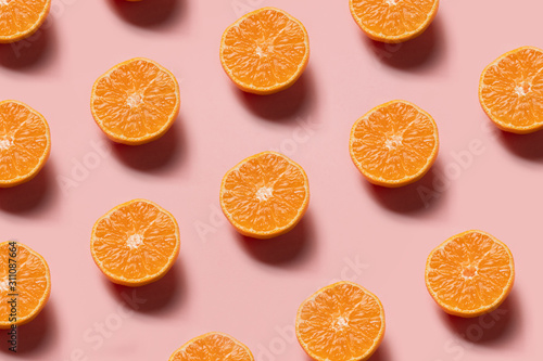 cut oranges in a row on pink background