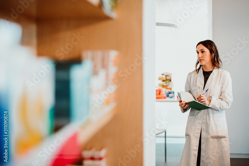.Young female pharmacist working in her large pharmacy. Placing medications  taking inventory. Lifestyle