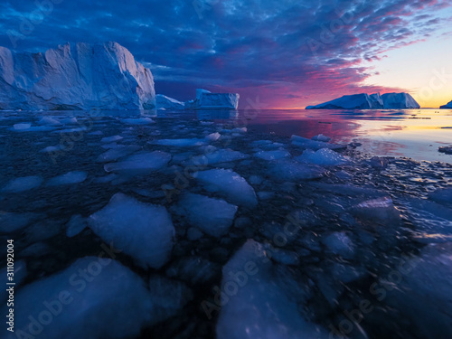 Iceberg at sunset. Nature and landscapes of Greenland. Disko bay. West Greenland. Summer Midnight Sun and icebergs. Big blue ice in icefjord. Affected by climate change and global warming. photo