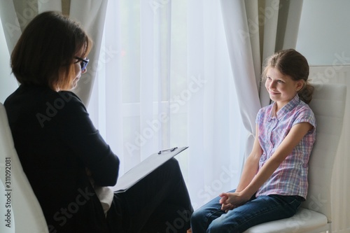 Meeting child girl with school counselor psychotherapist.