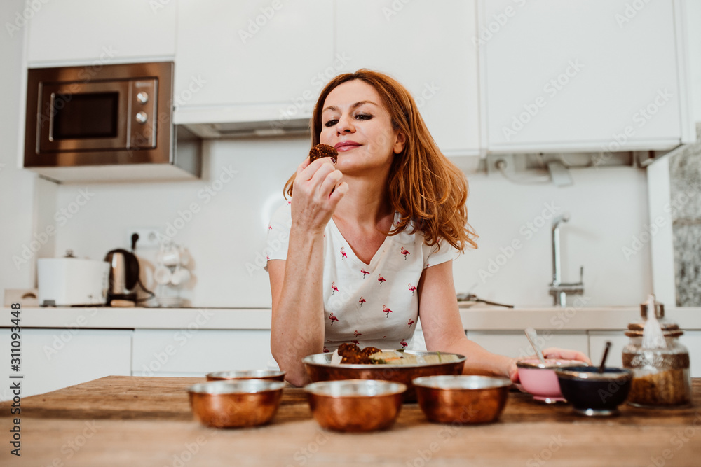 Beautiful red haired middle-aged woman cooking healthy food to stay fit and be in good healht. Relaxed and carefree. Lifestyle