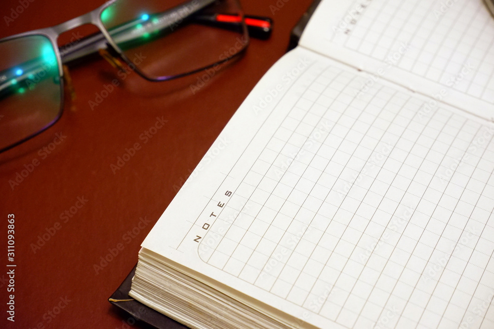 notebook and glasses on a brown background notebook and glasses on a brown background