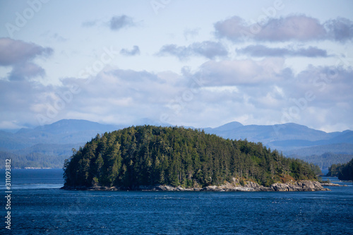 Northern Vancouver Island, British Columbia, Canada. Rocky Islands on the Pacific Ocean during a sunny and cloudy day with Islands and the Mainland in the background.
