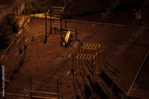 Aerial shot of an empty sport field at night in a dark yard with long shadows. One street lamp