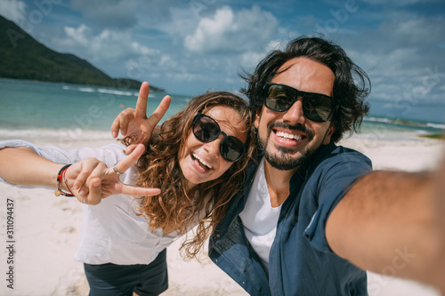 A pair of lovers take a selfie on a tropical beach.