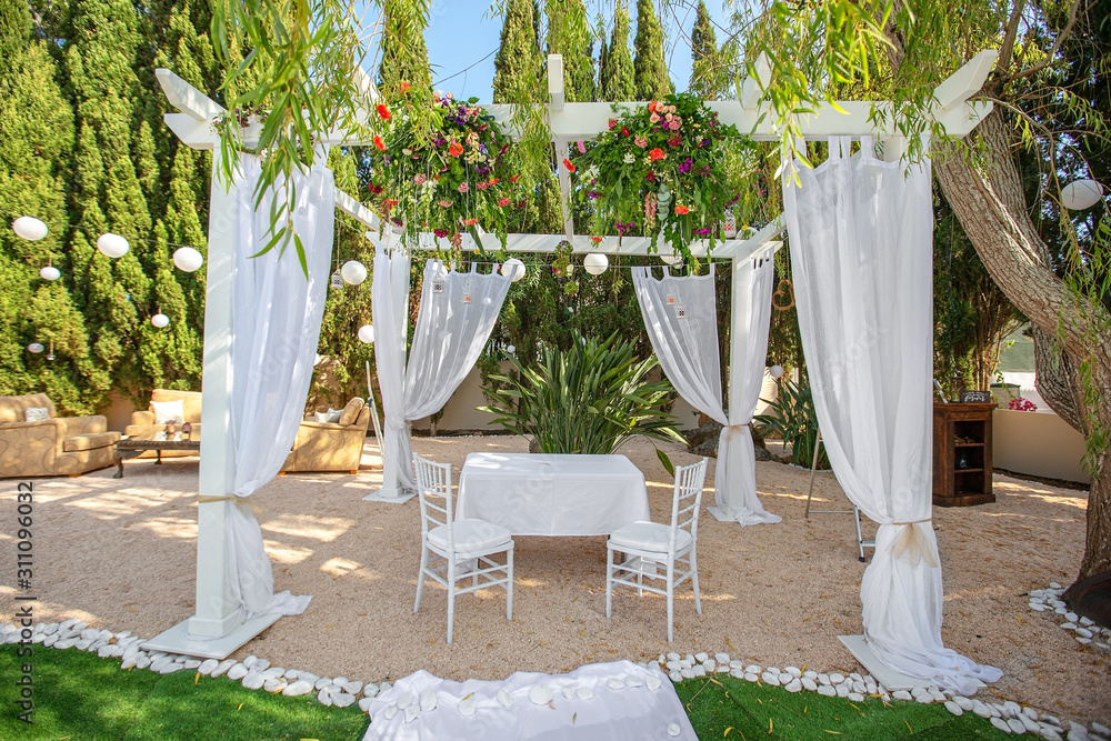 Decorations for the wedding ceremony in the garden. With an arch in flowers.