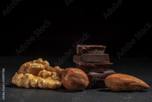Dark chocolate in nuts on a stone. Dark background