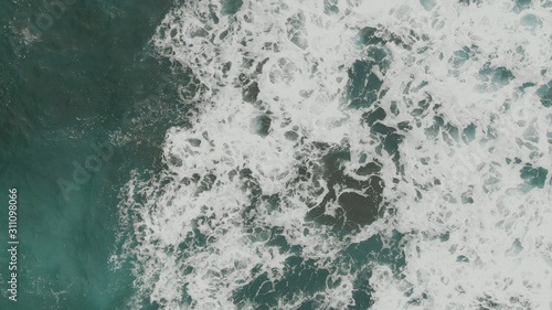 Top down aerial view of the ocean ripples and waves with foam