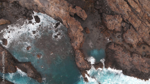 The natural pools of the island of Tenerife are a secret place. Aerial view. Cliffs of frozen lava and turquoise ocean