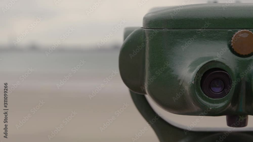 A handheld close up of the left half of a green viewfinder with the blurred vision of a seaside town in the background A handheld close up of the left half of a green viewfinder with the blurred vision of a seaside town in the background