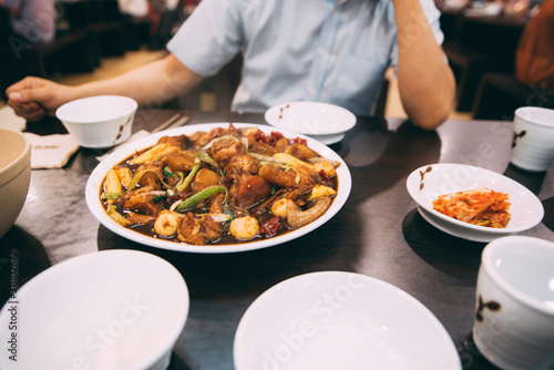 A Close up of Korean chicken dish on a table at a restaurant with a person in the background 