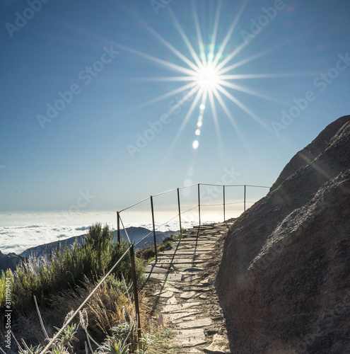 Path in picturesque mountainous landscape in Portuguese island Madeira on route to highest peaks between Pico Ruivo and Achada do Teixeira. Sun star in the sky.