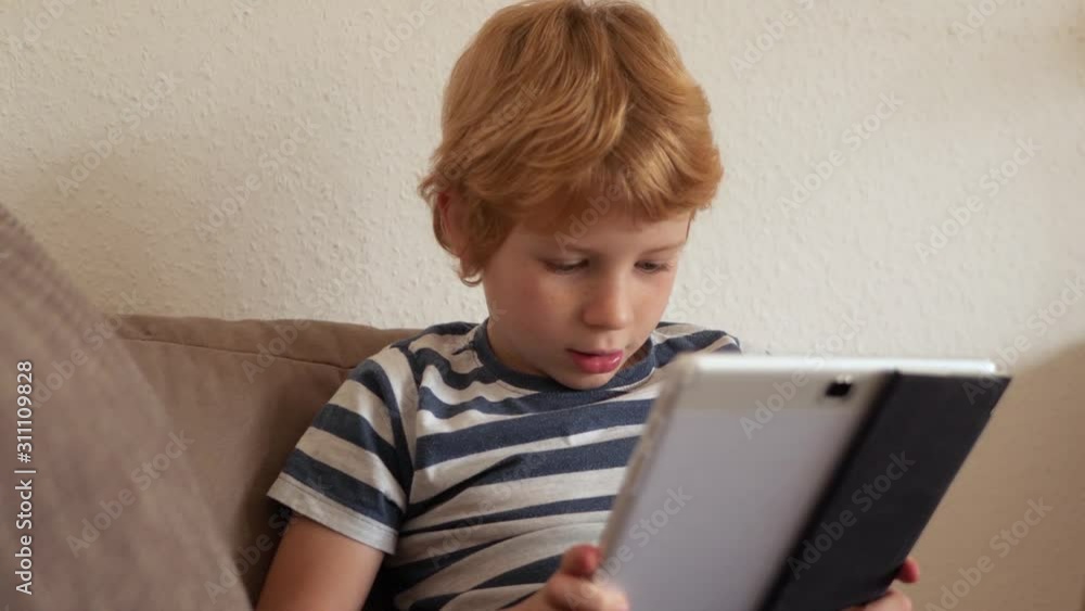 Portrait of young boy while surfing the internet on tablet. Portrait of young boy while surfing the internet on tablet.