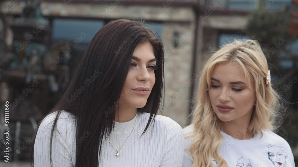 Portrait of two pretty blonde and brunette resting outdoors Portrait of two pretty blonde and brunette resting outdoors