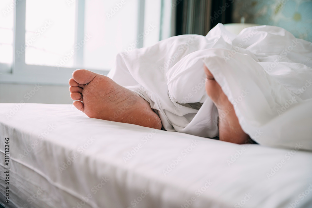 Close up of Human feet on a bed while sleeping in a bright room Close up of Human feet on a bed while sleeping in a bright room