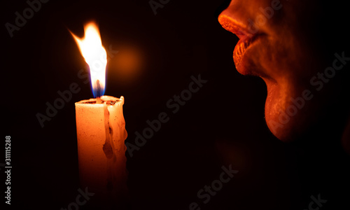 Woman blowing a candle with dark background