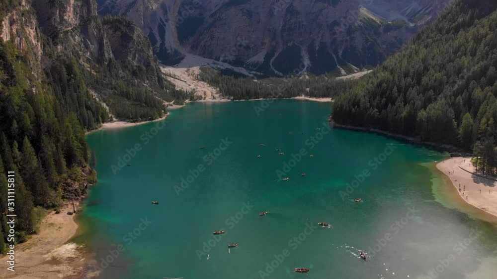 Lago Di Braies in the Dolomites. Drone view with boats in the crystal clear water and mountains behind Lago Di Braies in the Dolomites. Drone view with boats in the crystal clear water and mountains behind