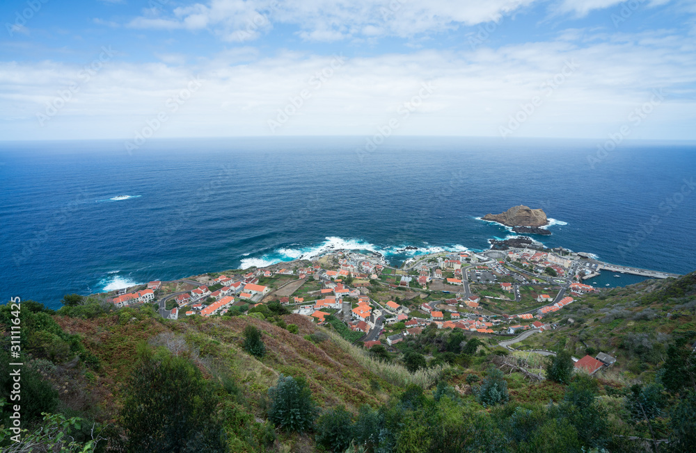 Aerial view from Miradouro da Santa onto Atlantic Ocean and it's tiny coastal municipality Porto Moniz with its oceanic swimming pools and cozy houses.
