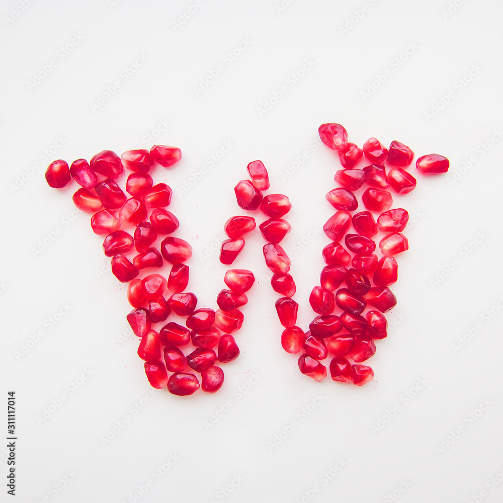 letter W folded from pomegranate berries on a white background top view letter W folded from pomegranate berries on a white background top view