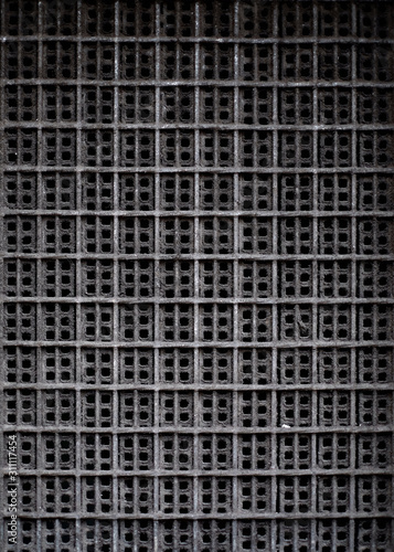 A dark rectangular pattern with repetitive square texture  an element of vent system  a minimal architecture detail.