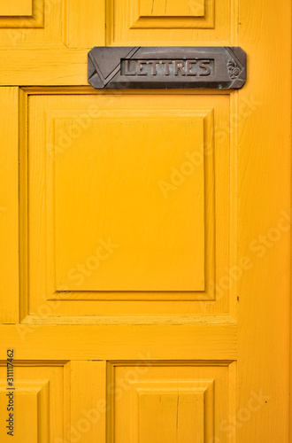 Orange door with a letter box and a French word LETTRES (English: MAIL).