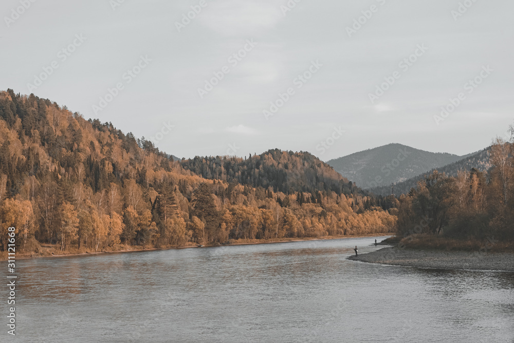 Men fishing with a fishing rod on the Bank of the Biya river, autumn forest in the Altai Mountains Men fishing with a fishing rod on the Bank of the Biya river, autumn forest in the Altai Mountains