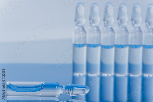Wallpaper Mural Glass medical ampoule vial for injection. Medicine is liquid sodium chloride with of aqueous solution in ampulla. Close up. Bottles ampule multicolor on background color and water. Human plasma. Torontodigital.ca