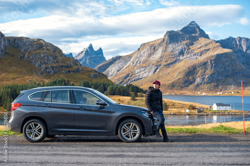 A man is standing with the car in Lofoten island, Norway