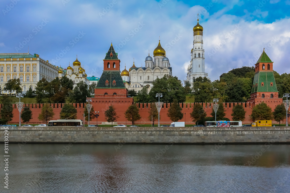 View of the red Kremlin wall, tower and golden onion domes of cathedrals over the Moskva River in Moscow, Russia