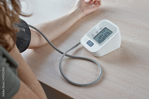 Woman measuring blood pressure with an electric digital tonometer.  Healthcare and medicine concept photo