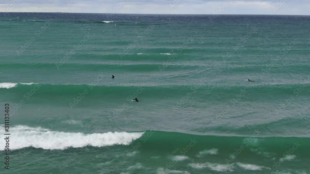 Surfing Waves in Charlevoix Michigan on a cool fall day in Blue Water with wet suits on they paddle out to ride a fresh water wave from one of America's Great Lakes rolling waves and waiting Surfing Waves in Charlevoix Michigan on a cool fall day in Blue Water with wet suits on they paddle out to ride a fresh water wave from one of America's Great Lakes rolling waves and waiting