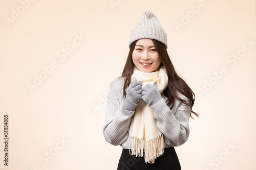 ベージュを背景にした冬服を着た若い女性のポートレート