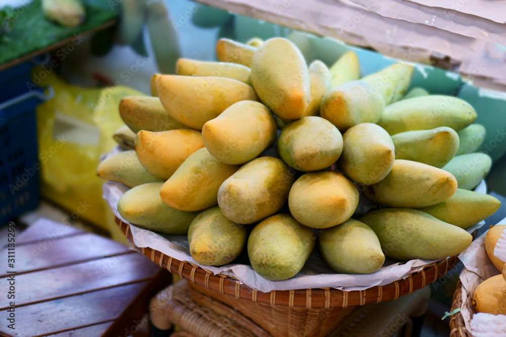Yellow nad green mangoes on a brown bamboo basket in the market