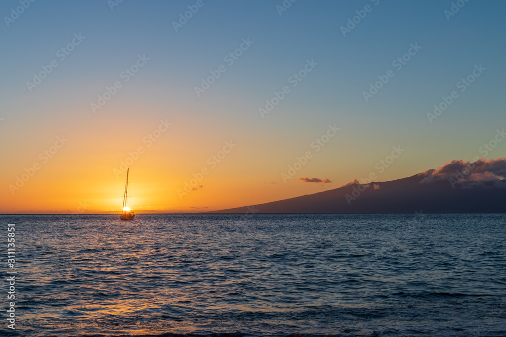 Lone boat anchored out at sea with islands in the background during sunset.