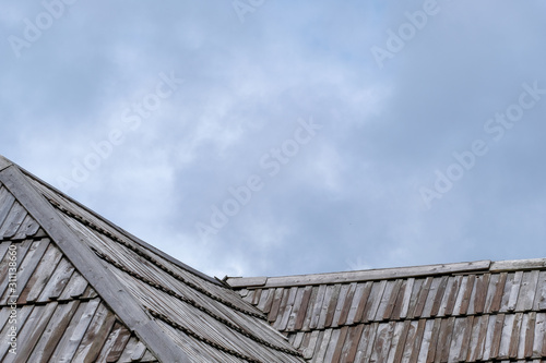 Wooden roof with cloudy sky in background.