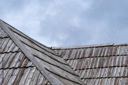 Wooden roof with cloudy sky in background.