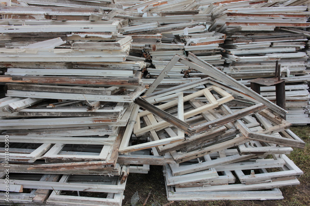 Heap of construction debris from old wooden window frames with glass outdoors. Reusable waste from old homes and buildings. Broken materials after upgrading window energy-saving technologies Heap of construction debris from old wooden window frames with glass outdoors. Reusable waste from old homes and buildings. Broken materials after upgrading window energy-saving technologies