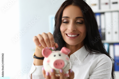 Cute woman putting money in moneybank photo
