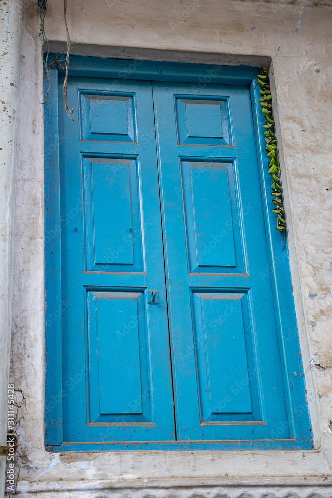 Bright blue door in an alley in Old Delhi India. Green chillies tied on a thread hanging to keep away Alakshmi, or Jyestha
