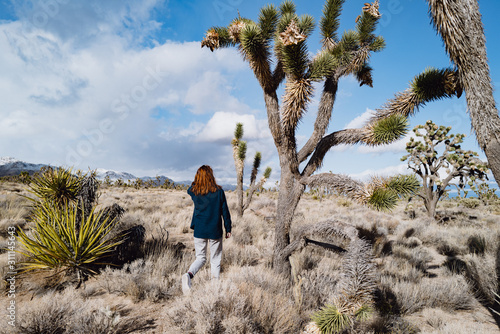 A girl in a vintage sweater hikes through the Mojave desert in winter near Joshua Trees