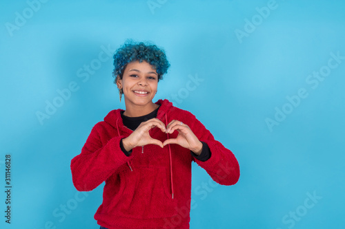 smiling girl with heart or love gesture isolated on color background