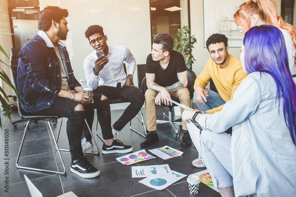 Group of multi ethnic executives discussing during a meeting. Business man and woman sitting around table at office and smiling. A team of young creative designers Group of multi ethnic executives discussing during a meeting. Business man and woman sitting around table at office and smiling. A team of young creative designers