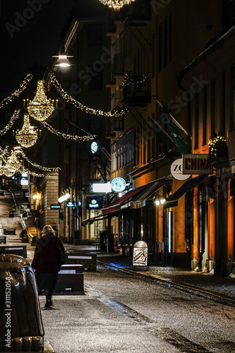 Fototapeta Naklejka Na Ścianę i Meble -  Stockholm, Sweden A lone pedestrian on Drottninggatan in the early morning at Christmas