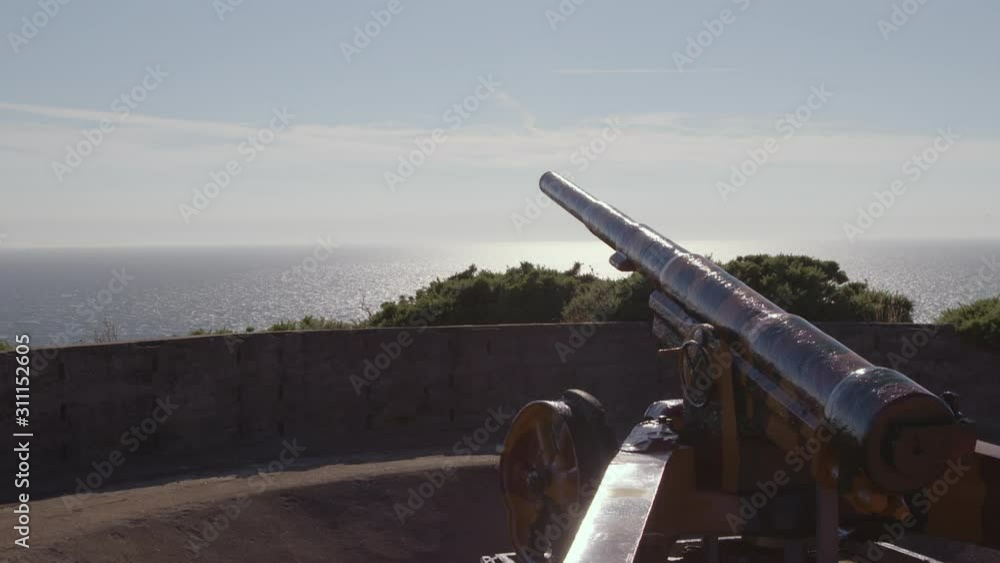 A daylight extreme closeup shot of an artillery gun display on top of a fort overlooking the horizon where the ocean meets the sky. A daylight extreme closeup shot of an artillery gun display on top of a fort overlooking the horizon where the ocean meets the sky.