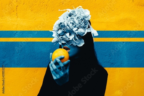 Female hand holding orange. Portrait Of Young Girl standing on color  background