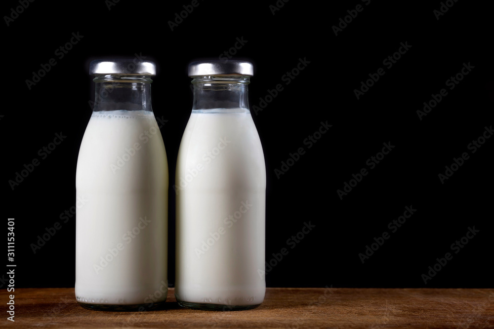Two glass bottles of fresh milk on a black background. Two glass bottles of fresh milk on a black background.
