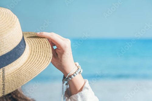 Woman in a straw on a beach with sea view.