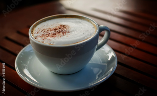 Blurred images of ready-to-drink cappuccino cups placed on a wooden table in the morning as background images and beautiful illustrations