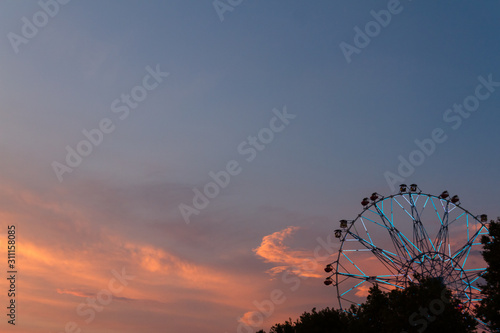 Silhouette of ferris wheel at sunset at county fair.
