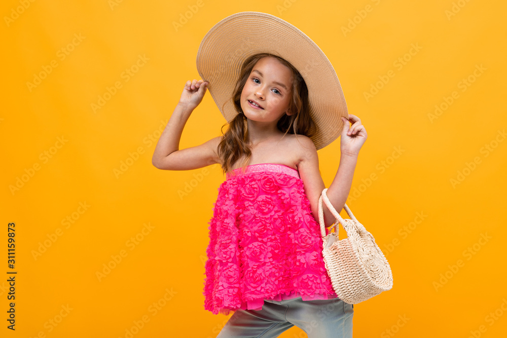 glamorous charming young child with a straw hat and a round bag on a yellow background glamorous charming young child with a straw hat and a round bag on a yellow background